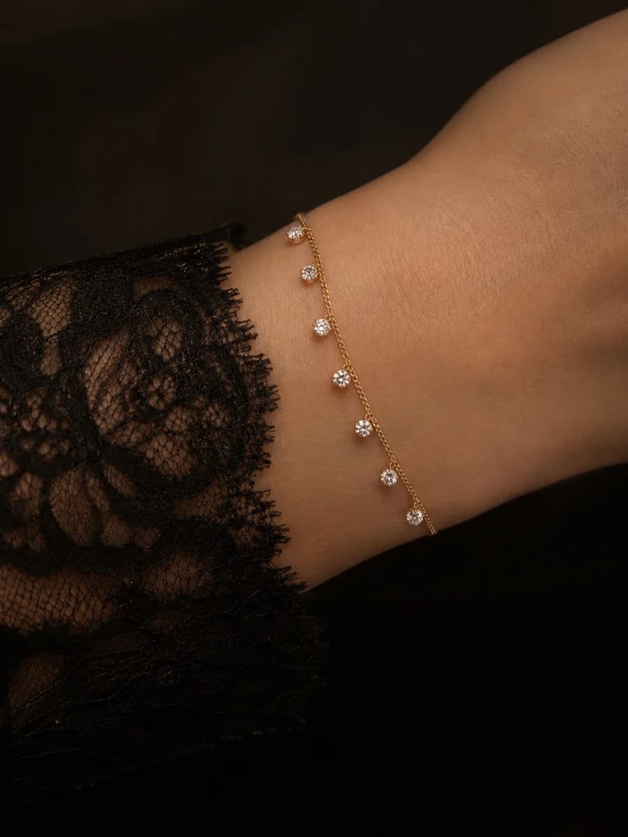 A gold-tone bracelet with four-point star charms, laid across cream silk.