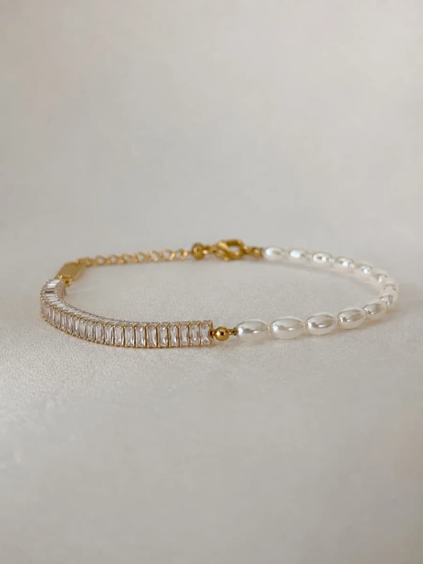 A bracelet featuring a half-section of rectangular clear crystals and a half-section of small, irregular pearl-like beads, laid on a light background.