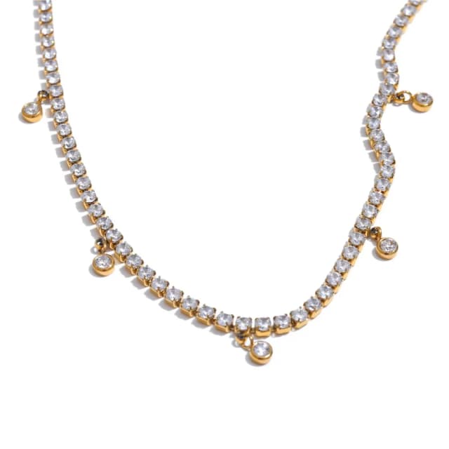 A gold-tone necklace with a continuous row of clear round crystals and several larger dangling crystal charms, on a white background.
